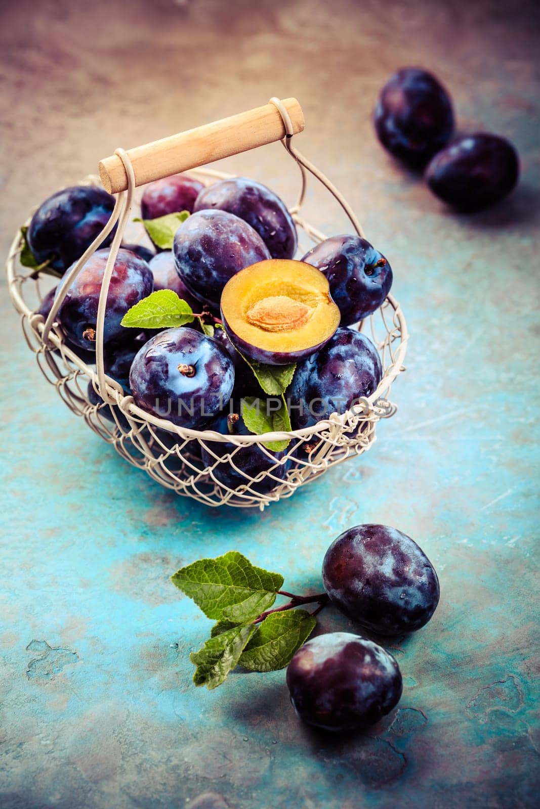Fresh plums in basket on dark stone background