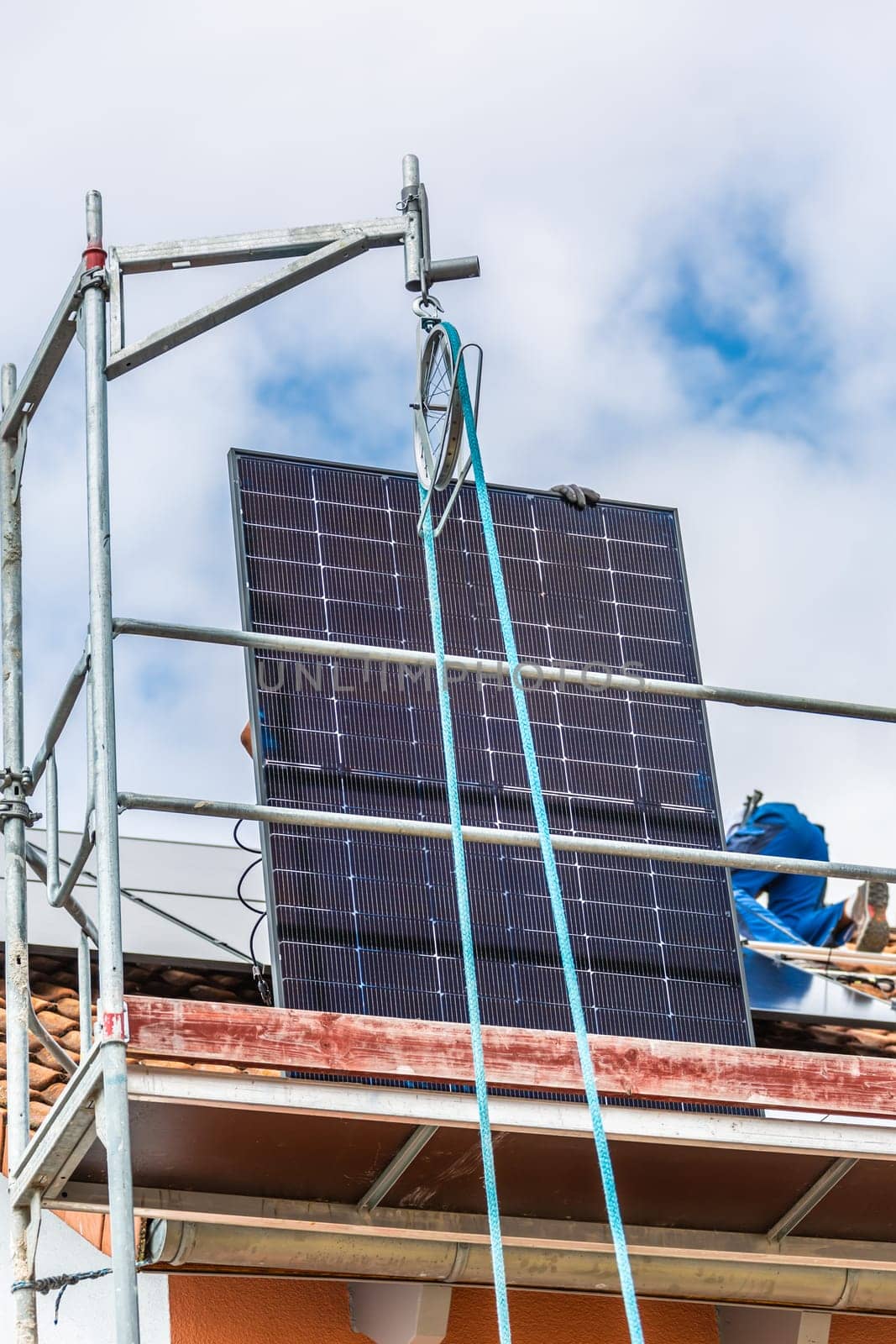 Lifting solar panels using pulley. Installing solar panels on a roof. Solar panels on roof. Workers installing solar cells.