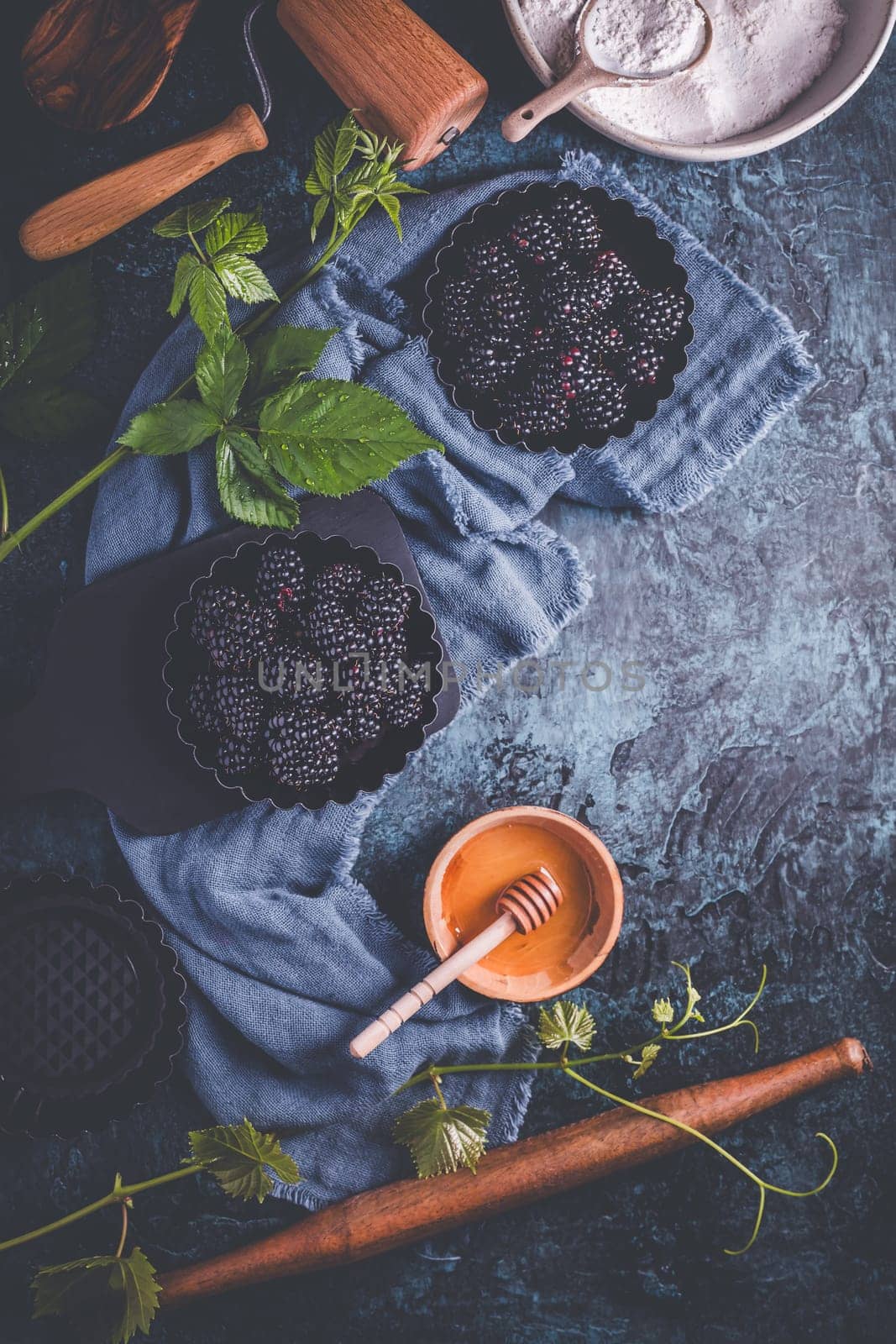 Organic blackberries in baking forms, ripe blackberries with baking ingredients and kitchen untensil