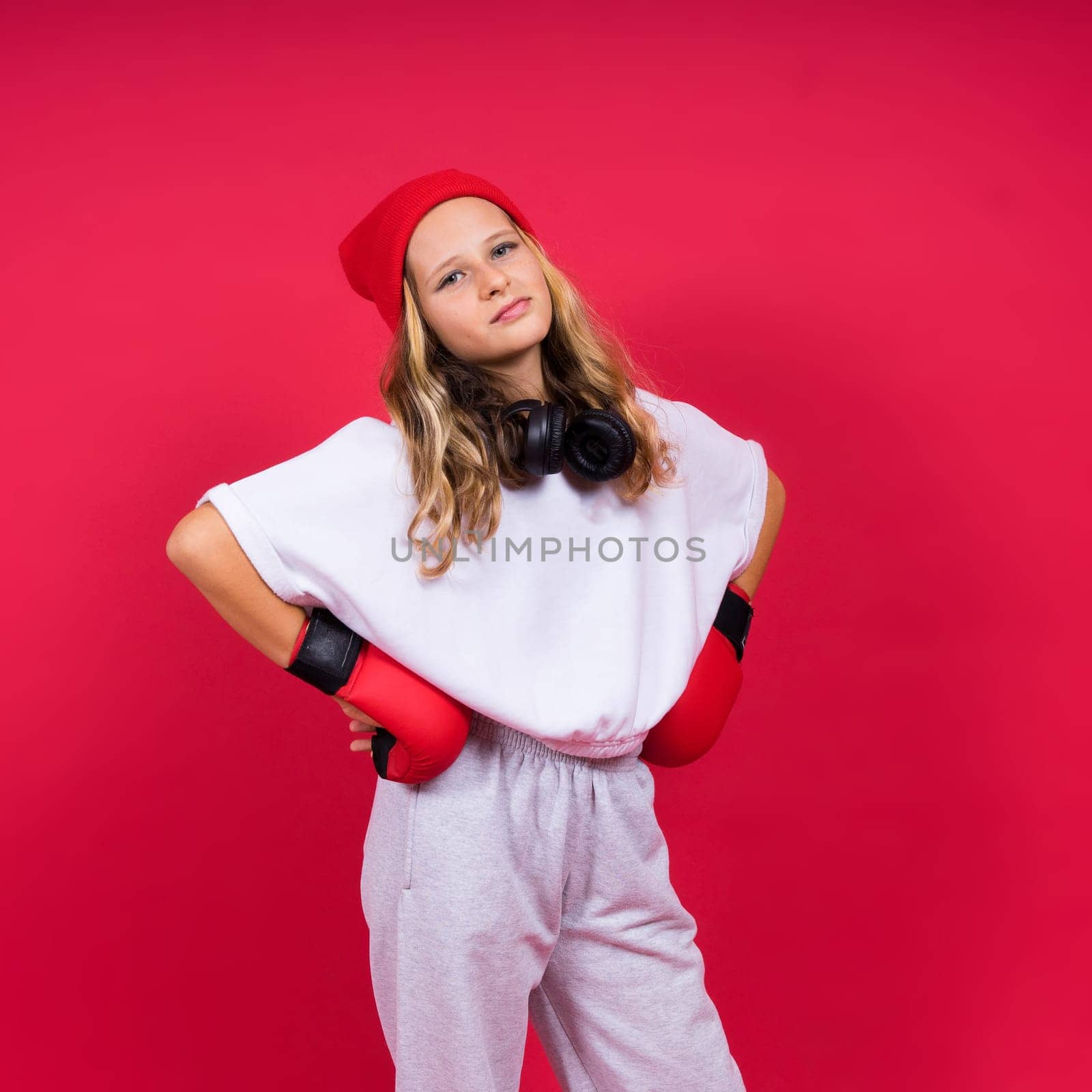 Cute little girl in boxing gloves on a red background studio