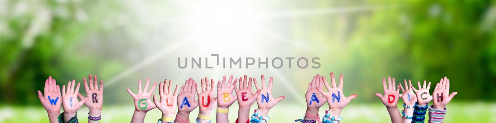 Children Hands Building Colorful German Word Wir Glauben An Dich Means We Believe In You. Sunny Green Grass Meadow As Background.