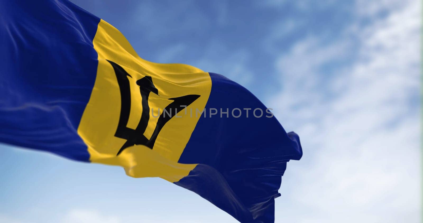 Barbados national flag waving in the wind on a clear day. Blue and yellow flag with a black Triton in the center. 3d illustration render. Rippled Fabric. Selective focus.
