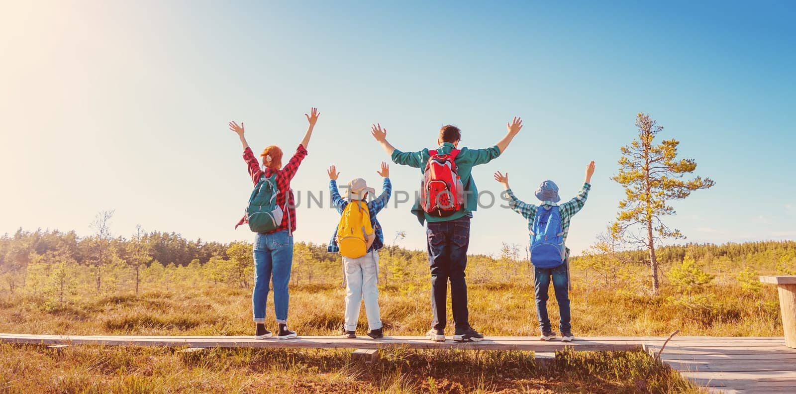 Family standing on the nature with rising nands. Concept of the freedom, tourism and hiking.