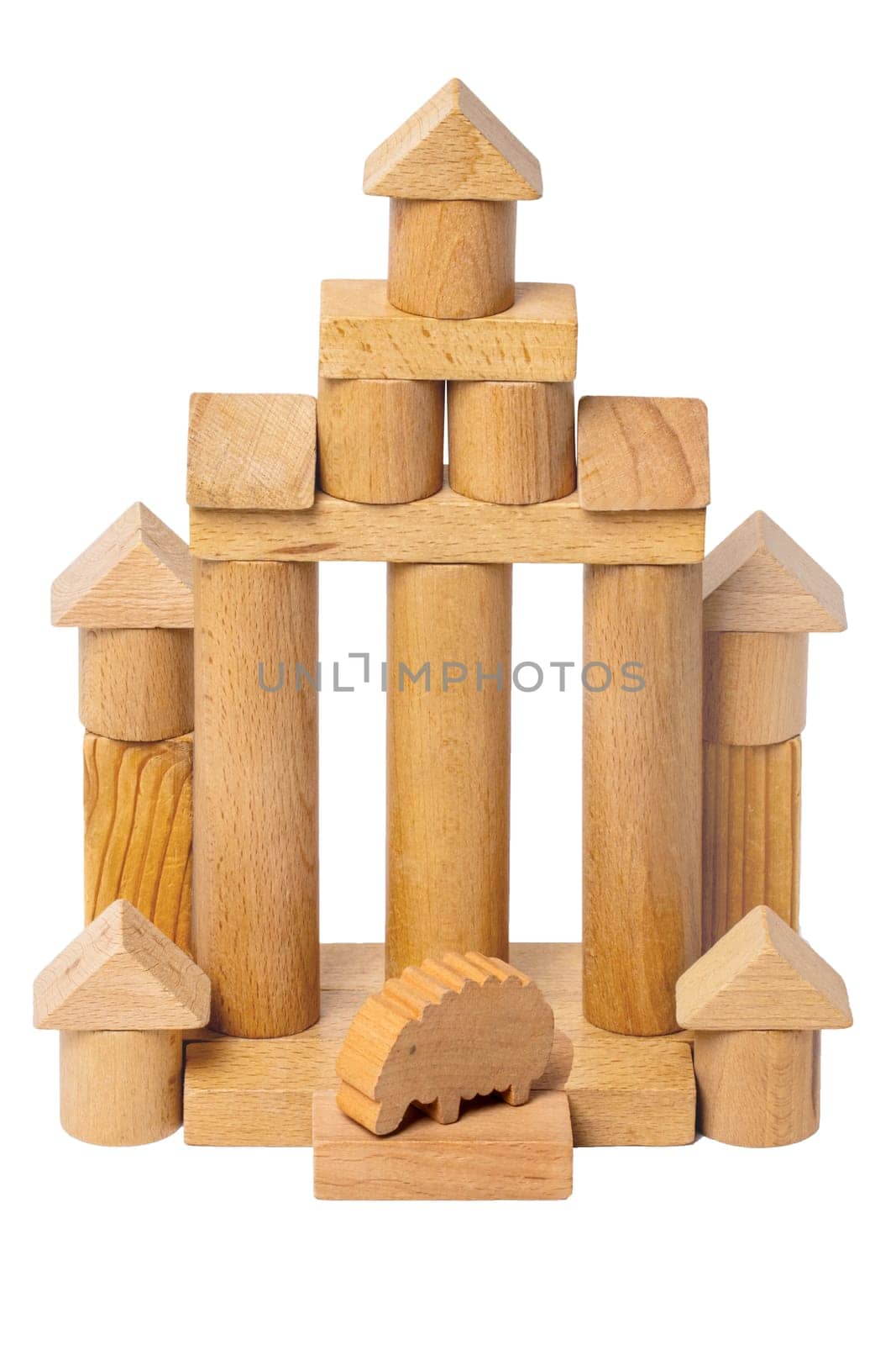 Isolated house made of wood. Wooden toy castle made of cubes, cylinders, triangles and a sheep at the entrance. Wooden toy blocks. Macro.
