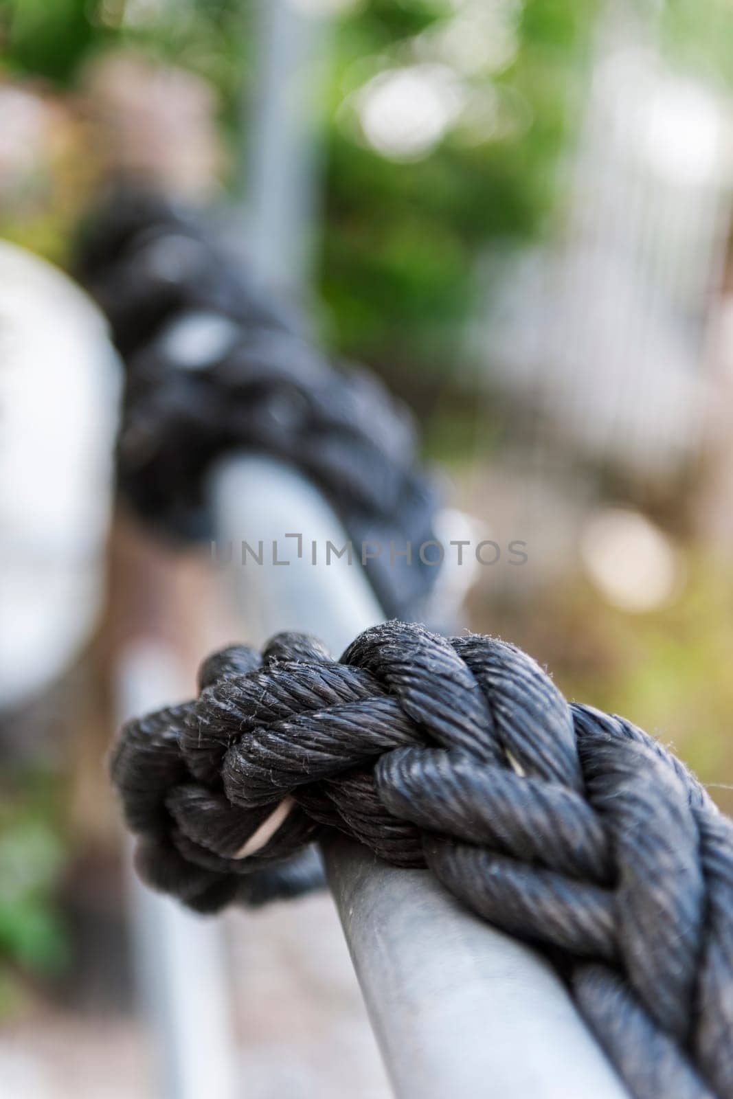 Perspective view along a railing with a plastic rope leading into the blur.