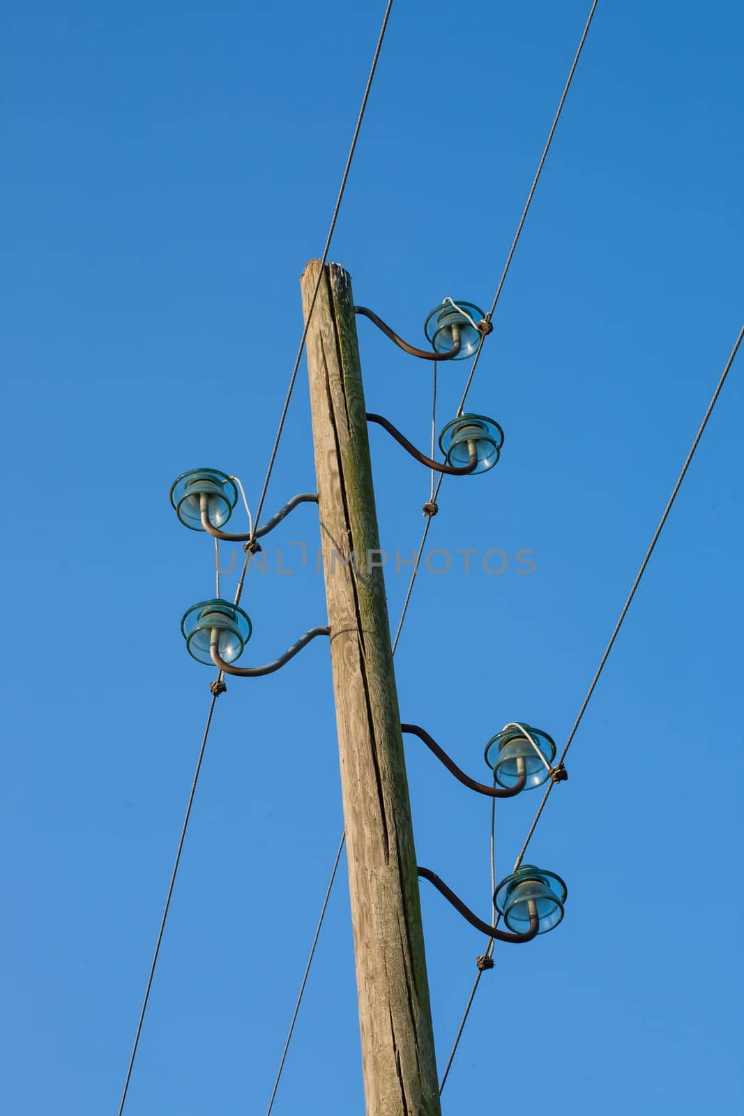 A wooden electric pole, on a blue background with the moon in the background.