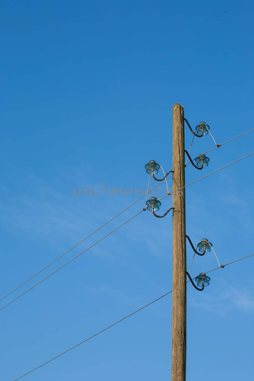 A wooden electric pole, on a blue background with the moon in the background.