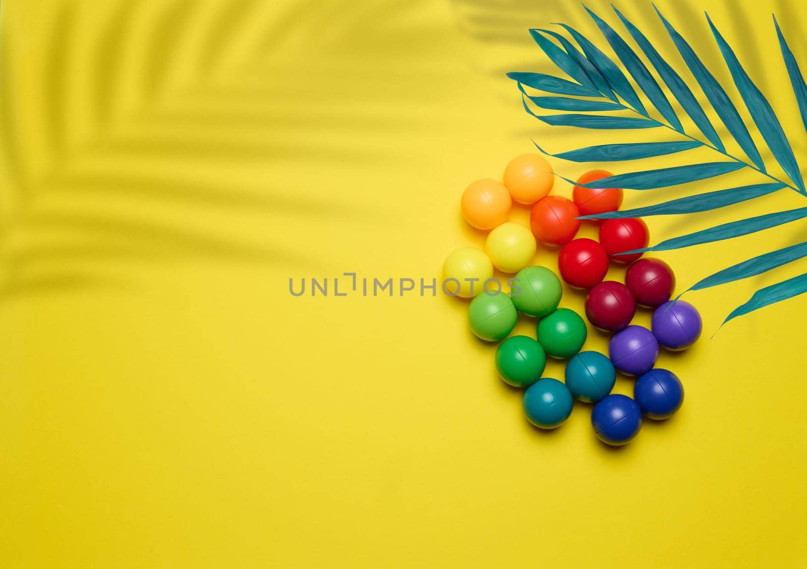 Abstract background with multi-colored plastic balls on a yellow background, a stage for the demonstration of cosmetics and products