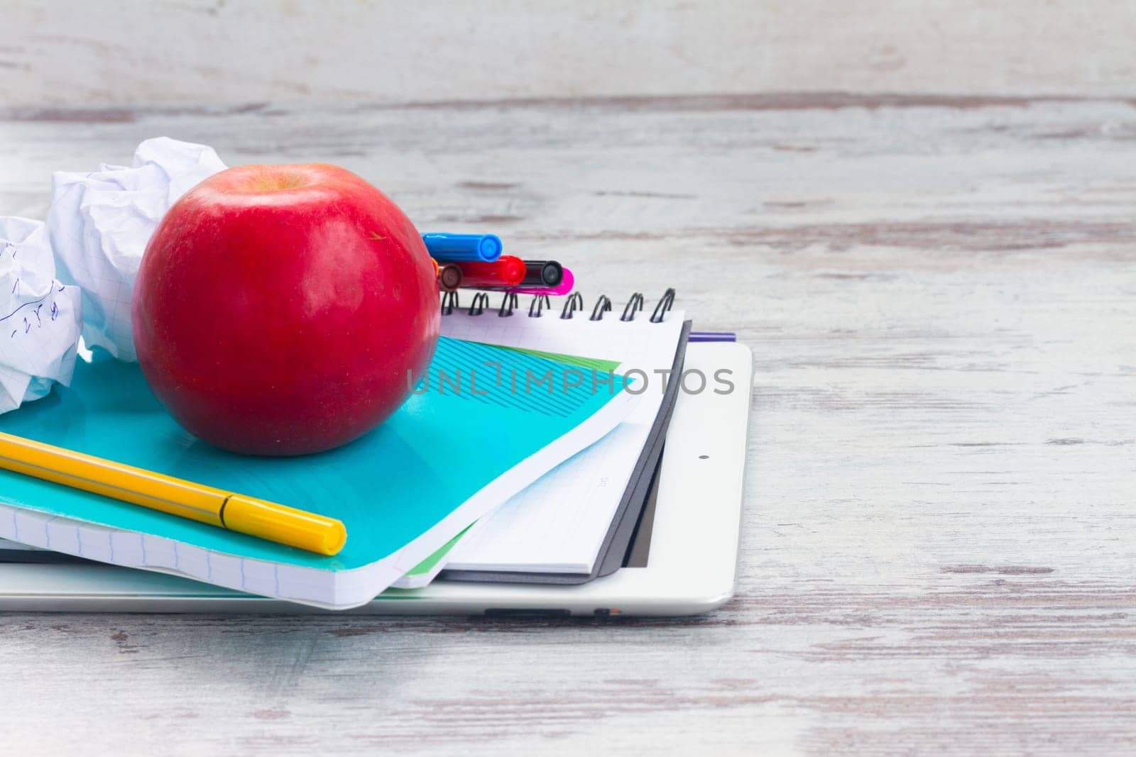 Apple with school supplies on white aged wooden table