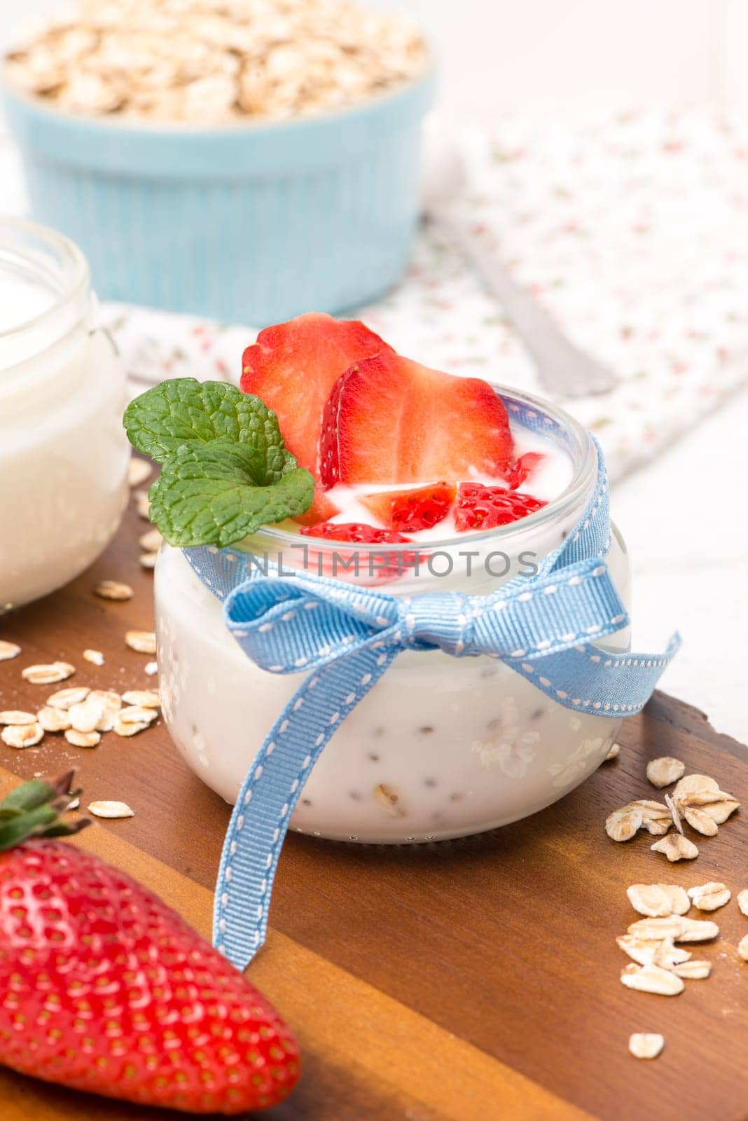 Strawberries desert with cream and cereals served on glass cups over table top.