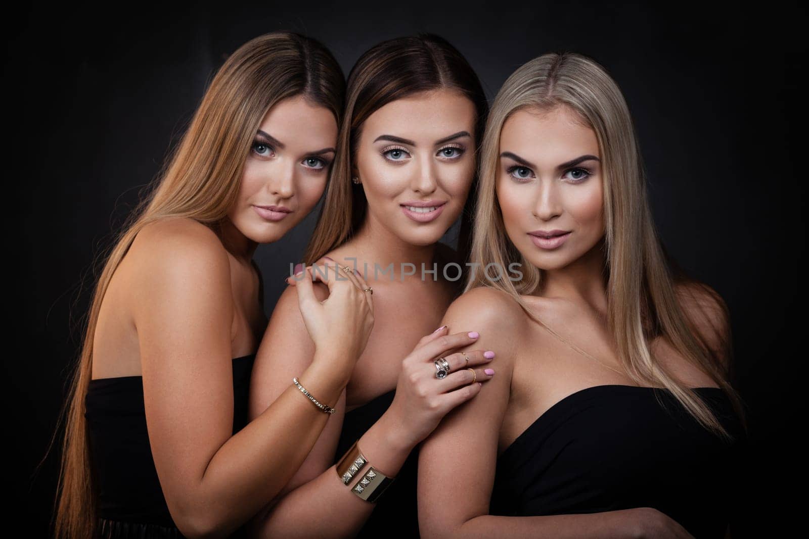 Three sexy girls in casual clothes posing on dark background