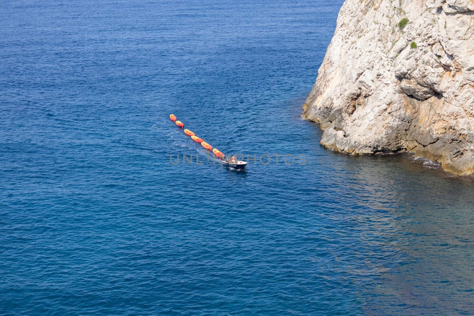 Dubrovnik, Croatia - June 27, 2023: Transportation of colorful kayaks for tourists by water on the Adriatic Sea to the West Harbour next to Fort Lovrijenac and City Walls
