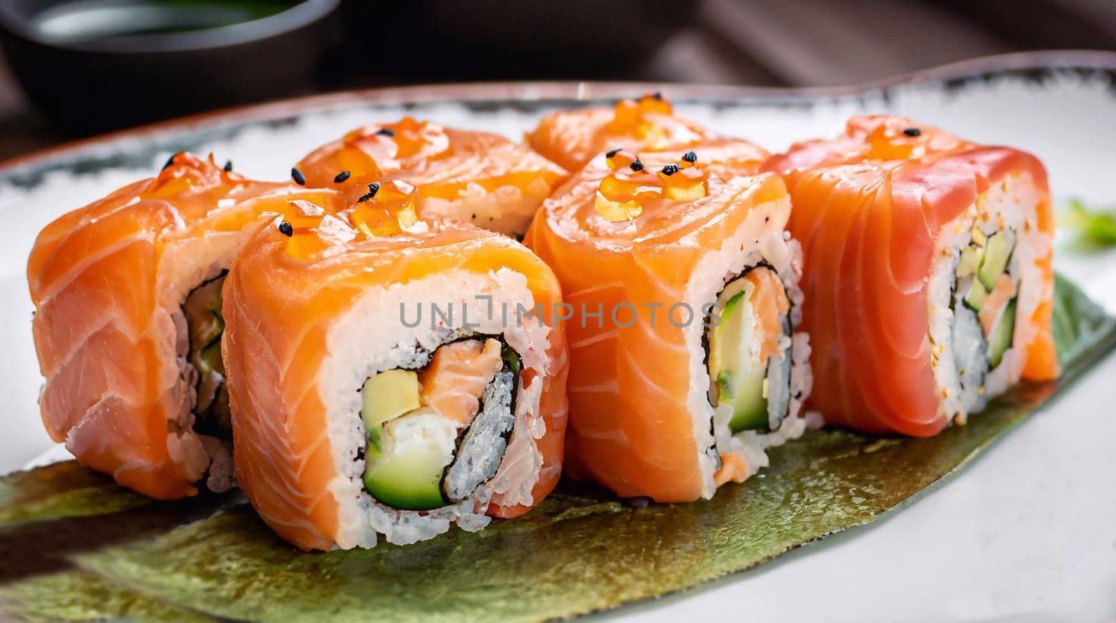 Eating Sushi with chopsticks. Sushi roll japanese food in restaurant. California Sushi roll set with salmon, vegetables, flying fish roe and caviar closeup. Japan restaurant menu