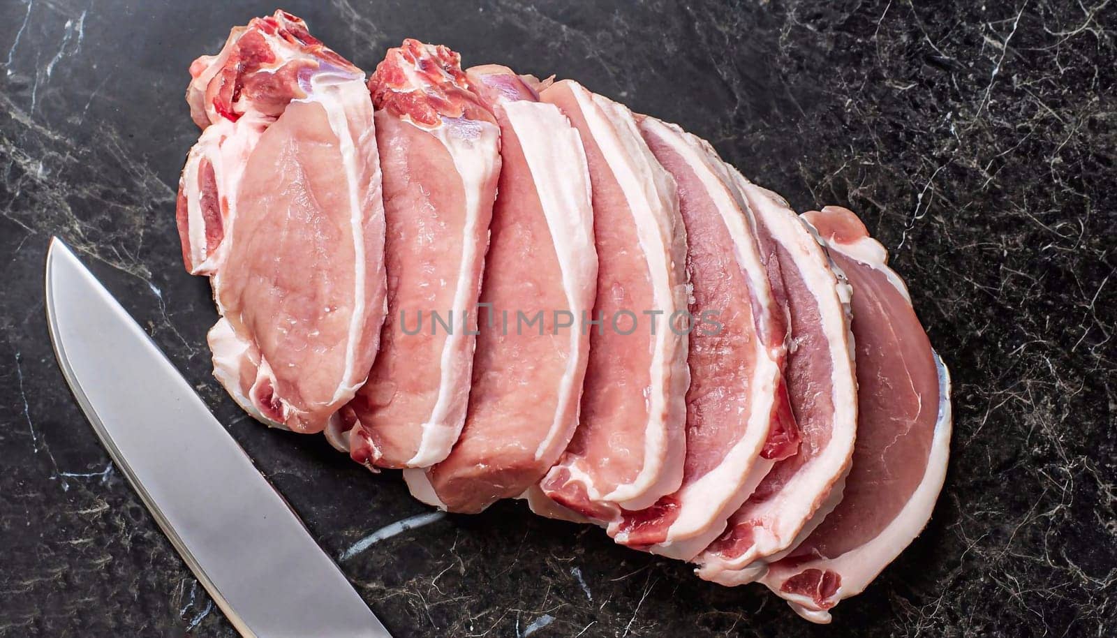 Sliced raw pork meat with meat knife on dark background