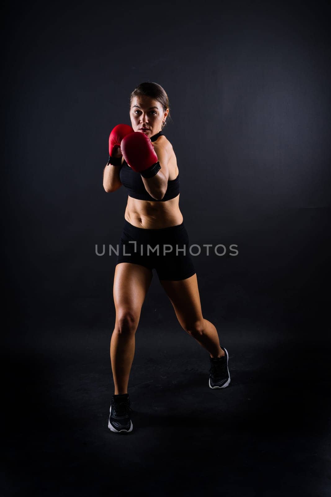 Portrait of female mixed martial arts fighter with a bandage and gloves on her hands.