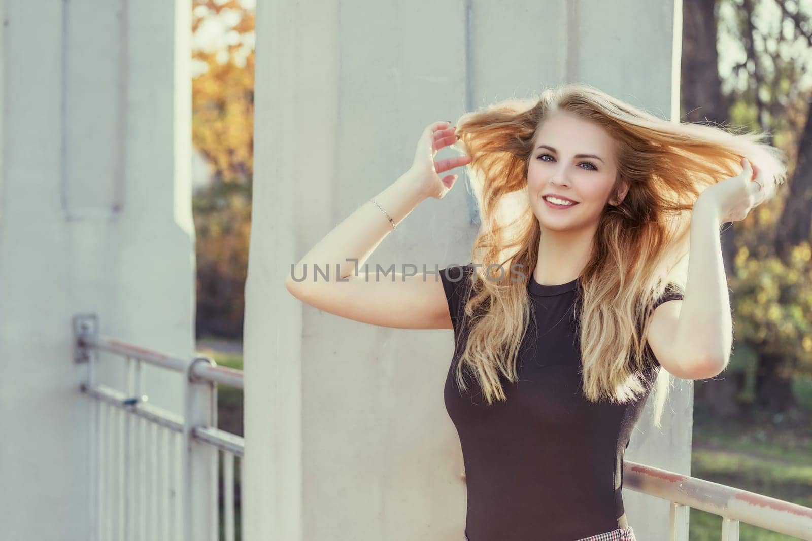 Attractive girl with flowing hair is  laughing at camera outdoors. Horizontally.