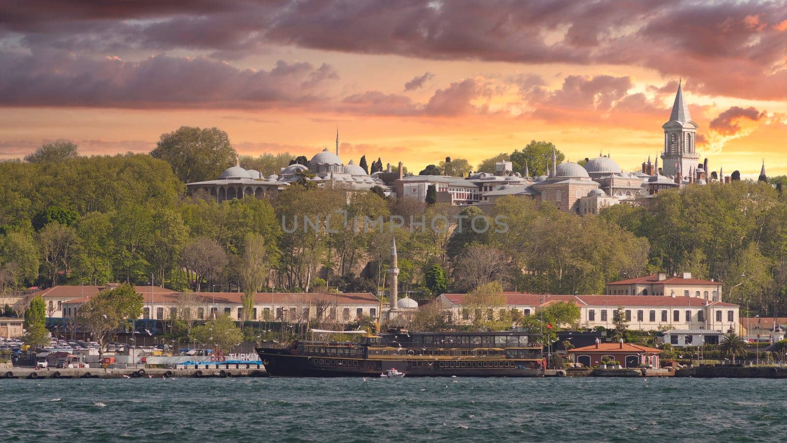 View from Galataport overlooking Bosphorus strait with sailing ferry boat and Topkapi Palace in the far end before sunset, Istanbul, Turkey
