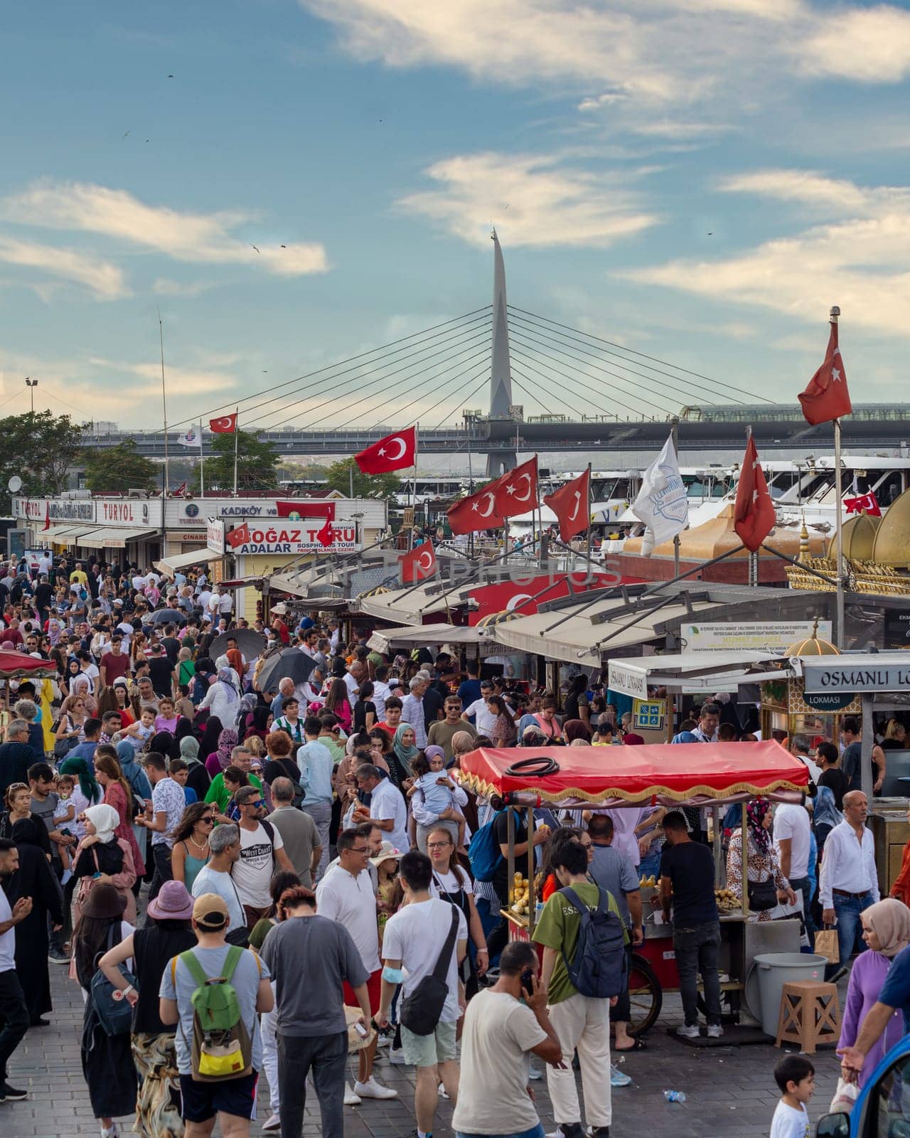 Istanbul, Turkey - August 30, 2022: Crowds of local citizens at Eminonu Plaza during the Victory Day holiday with background of Istanbul city view including Golden Horn Metro Bridge