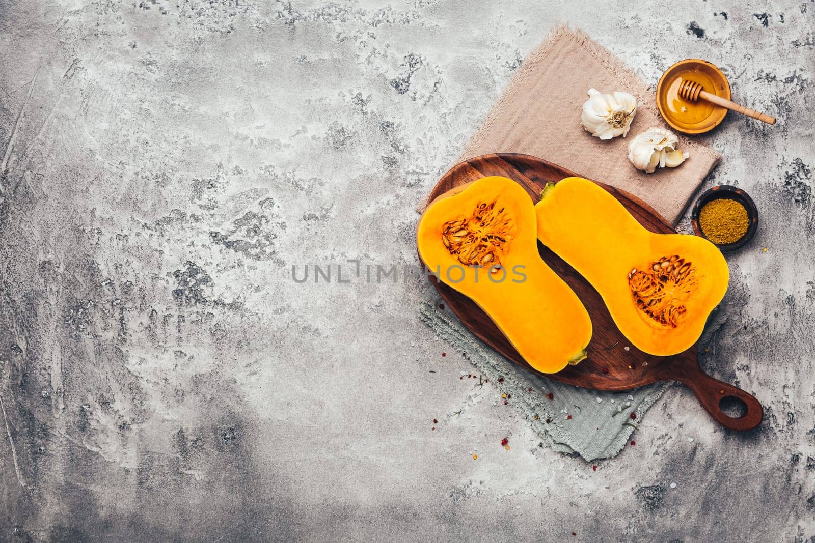 Halves of raw organic butternut squash with spices and ingredients for cooking