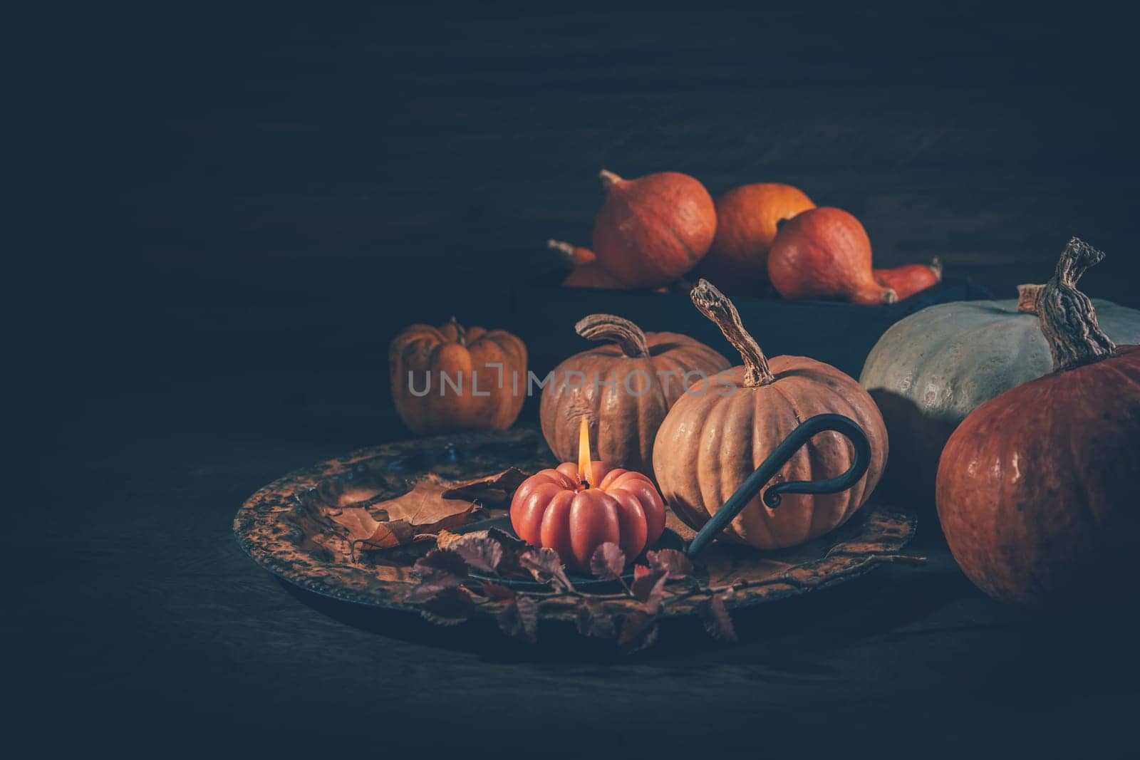 Autumn or fall harvest concept with pumpkins and candles on dark wooden background