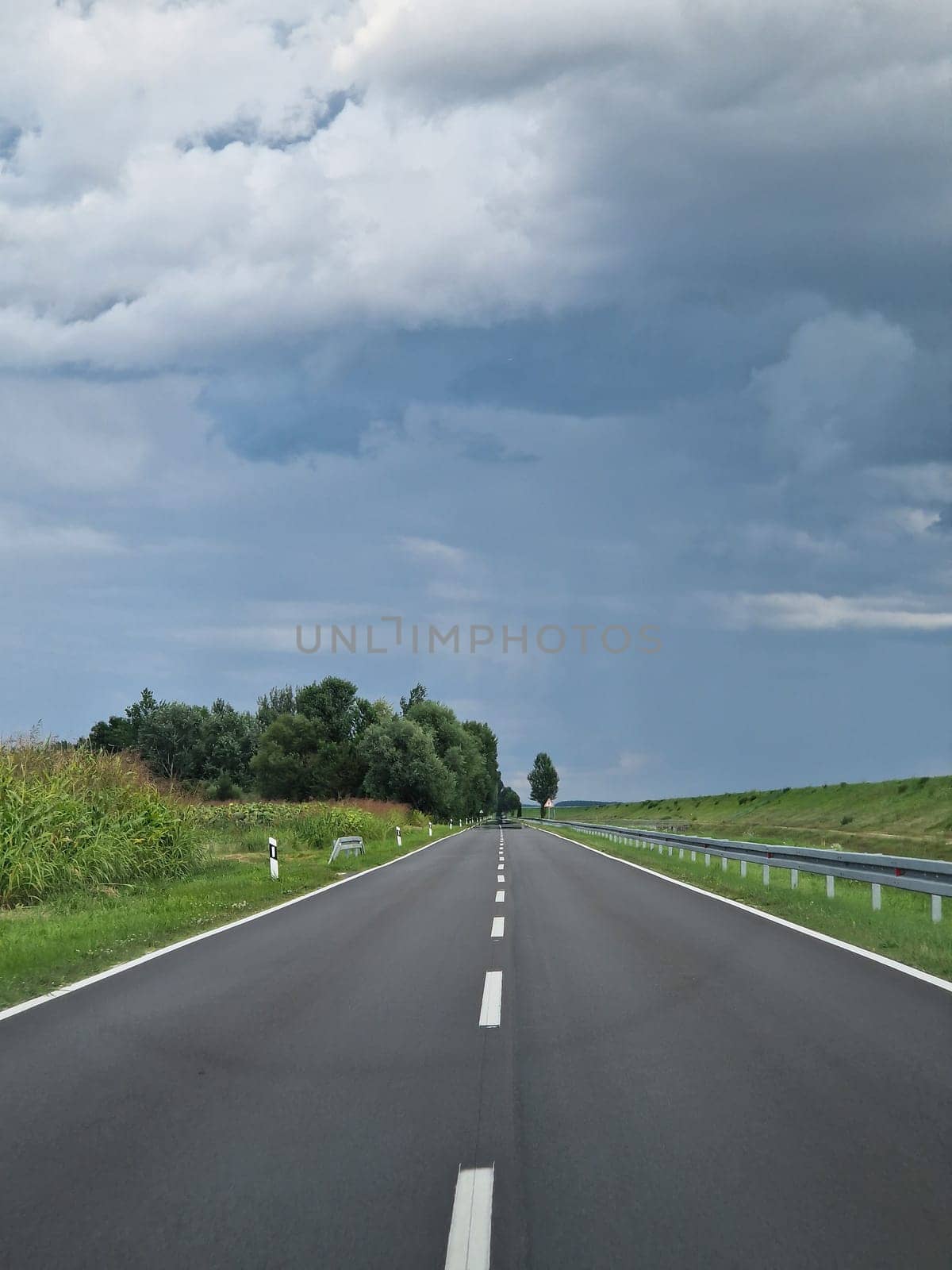 POV- Driving on a straight road, cloudy sky and green surroundings