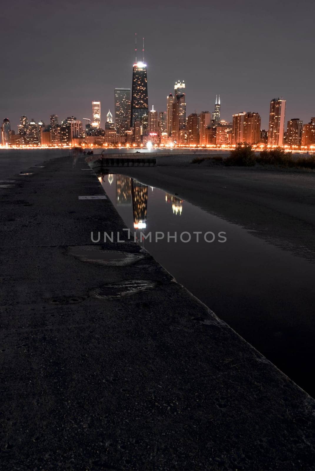 Chicago night skyline with partial beach and water reflections