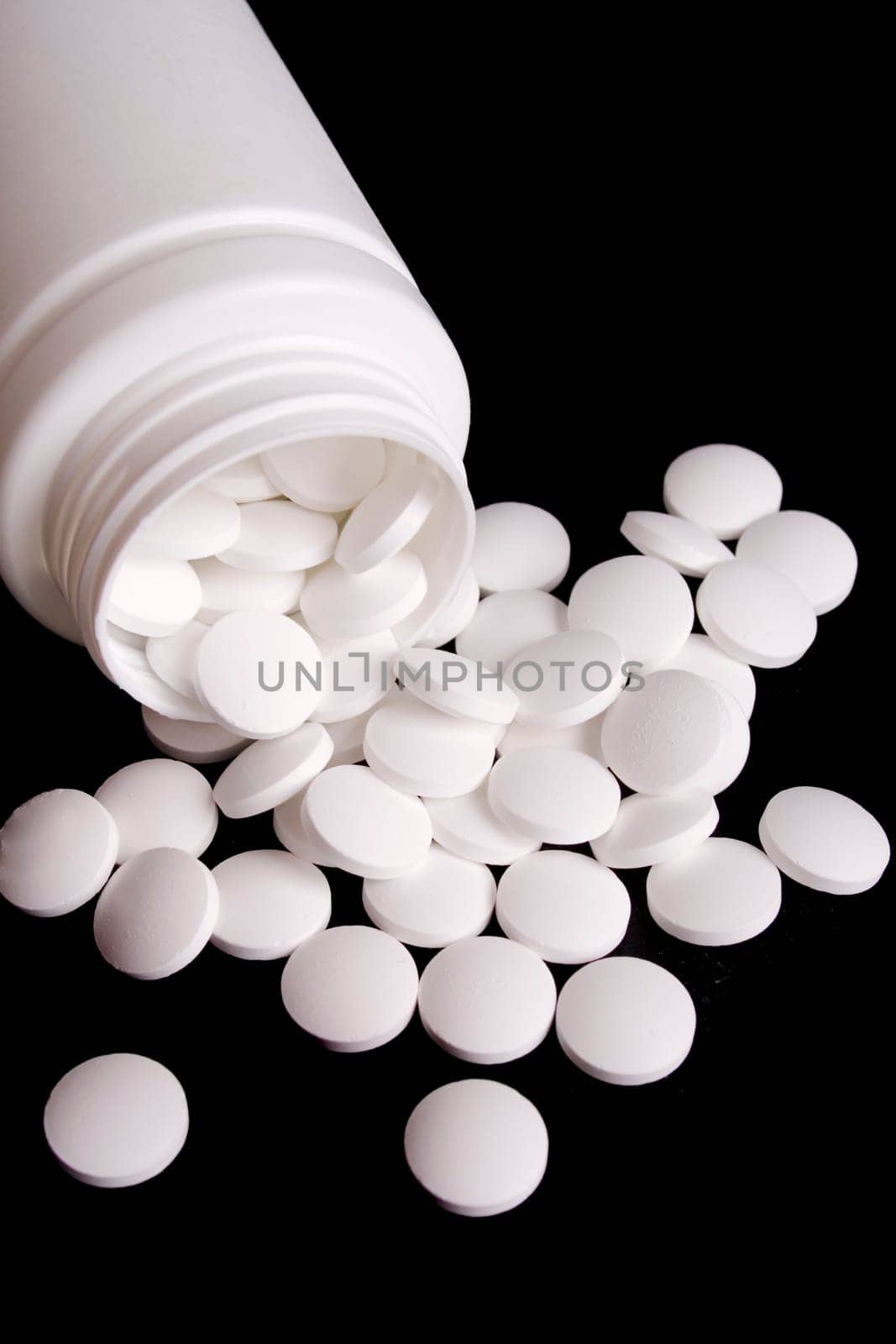 bottle with white pills on black background