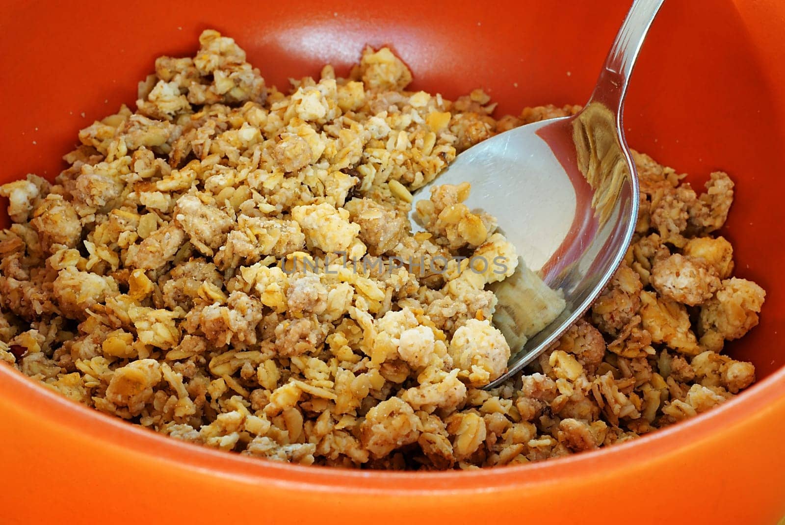 Orange bowl with cereals and metal spoon