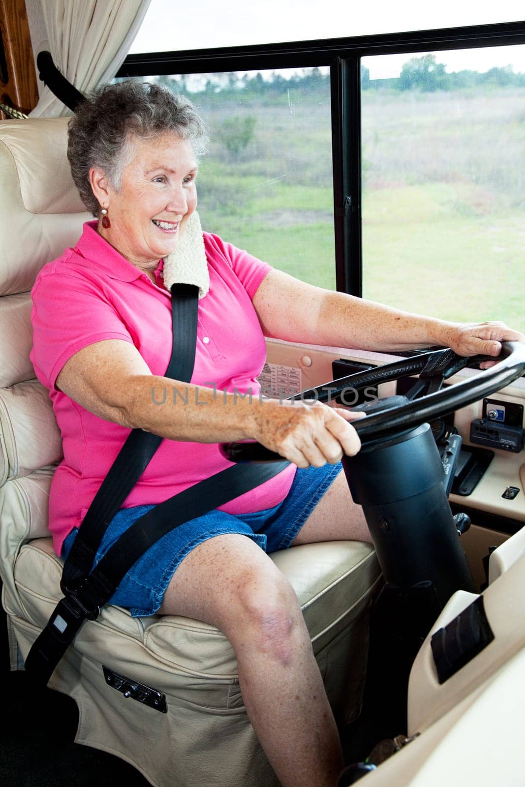 Senior woman enjoys driving her luxury motor home.