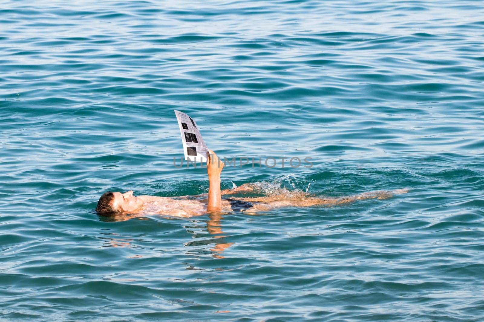a man is lying on the water reading newspaper