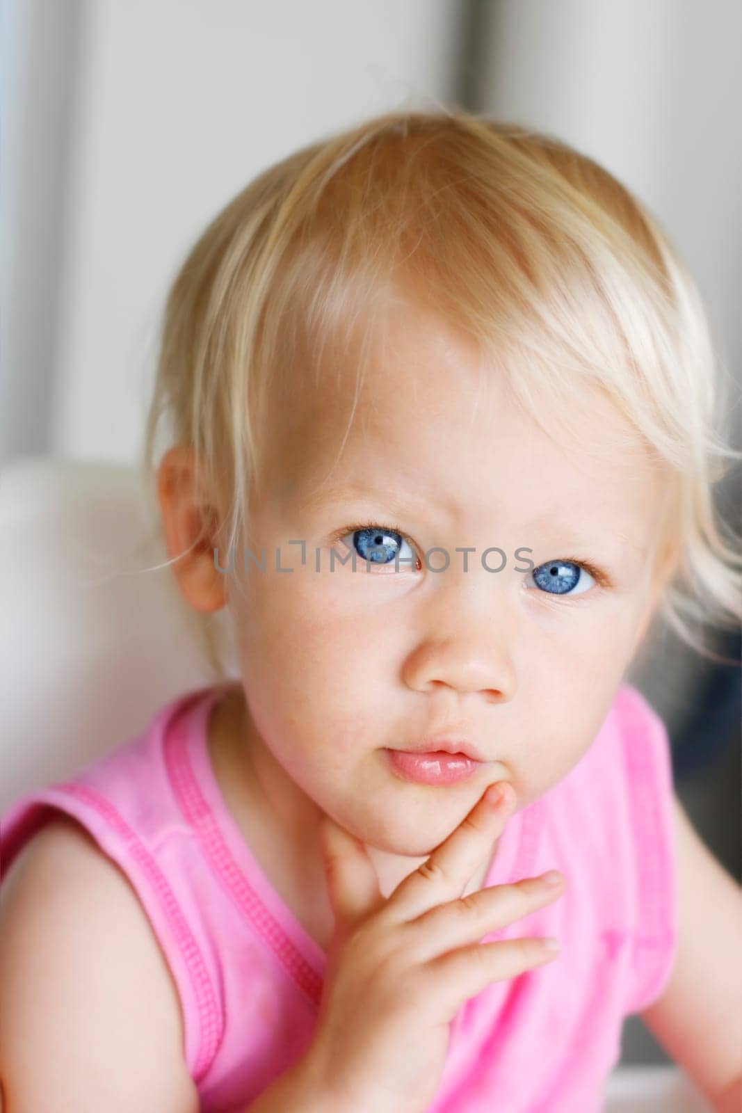 A close-up portrait of a toddler with a thoughtful expression.