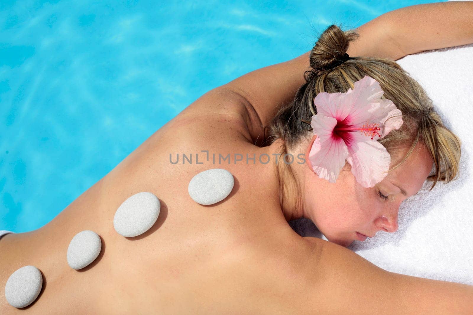 Woman with massage stones by a blue pool