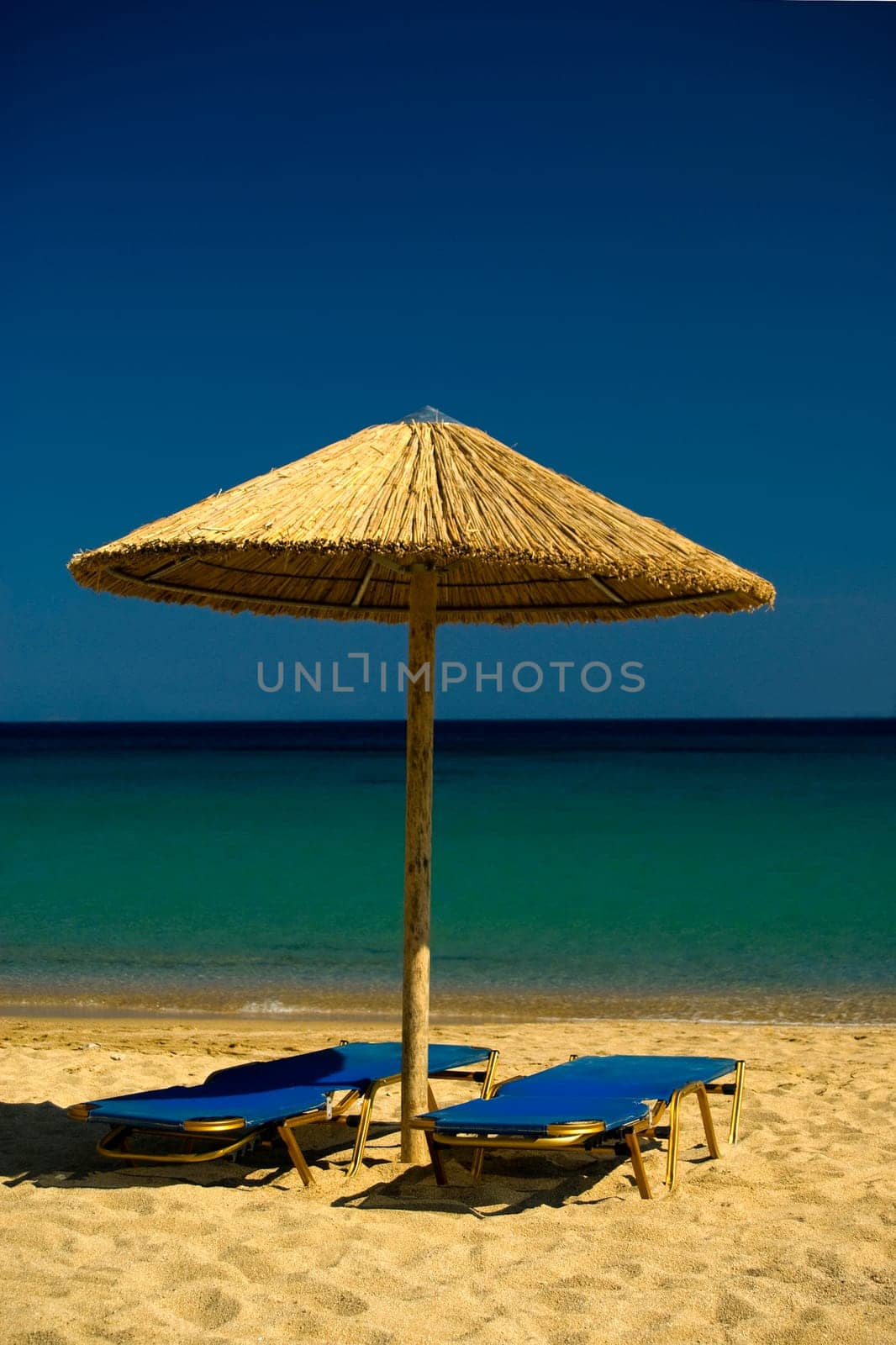 Two lounge chairs and umbrella  on Paradise Beach , Mykonos , Greece.