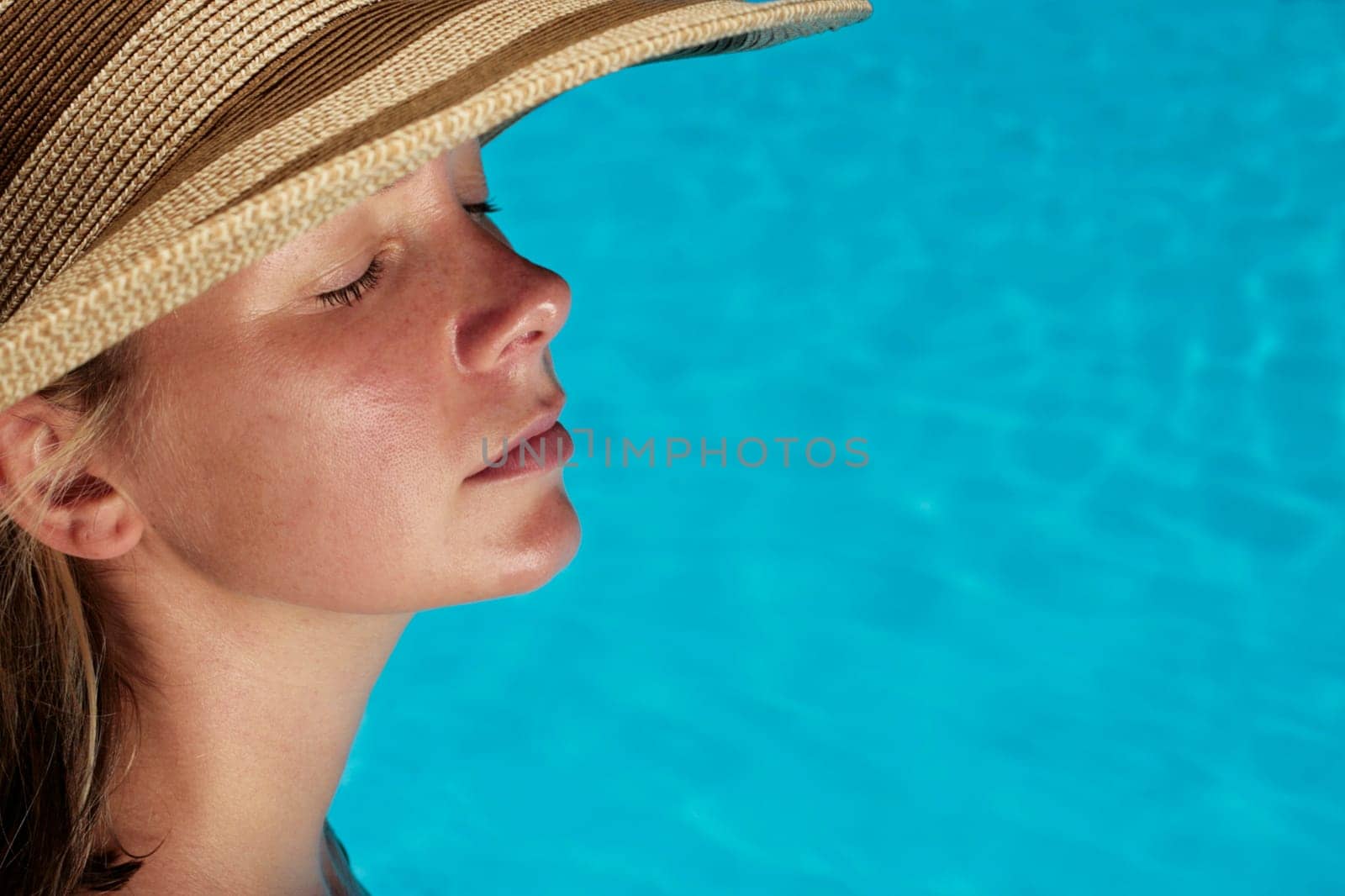Woman sunbathing by blue swimming pool