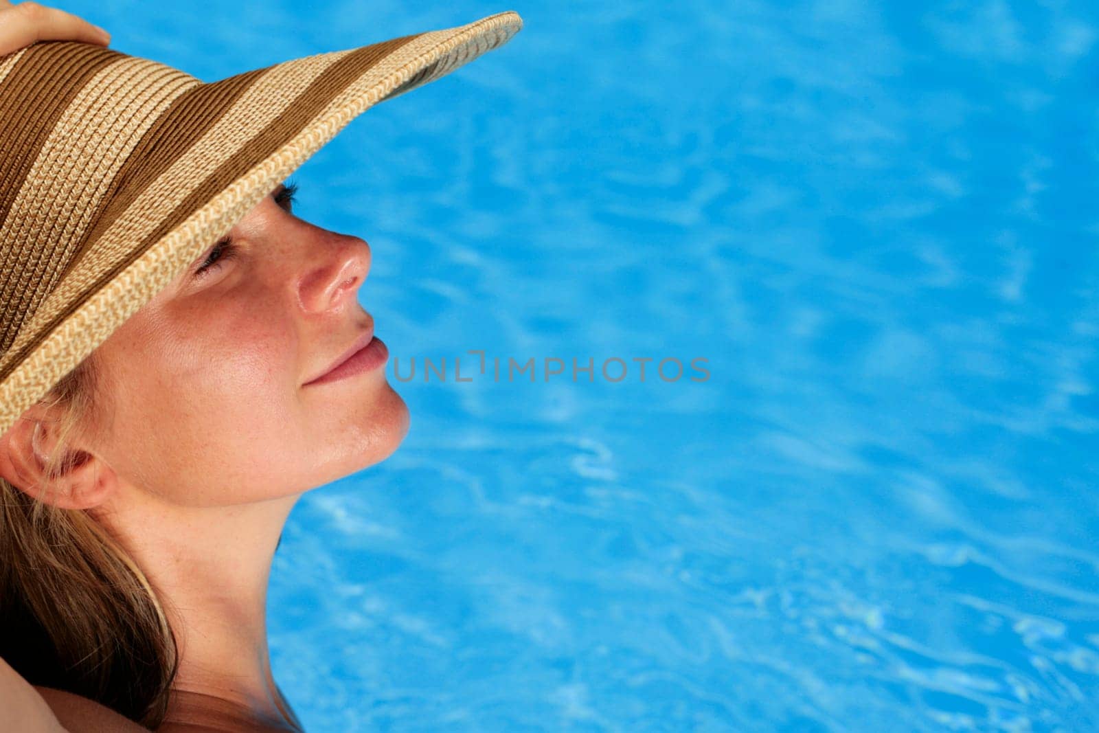Woman sunbathing by blue swimming pool