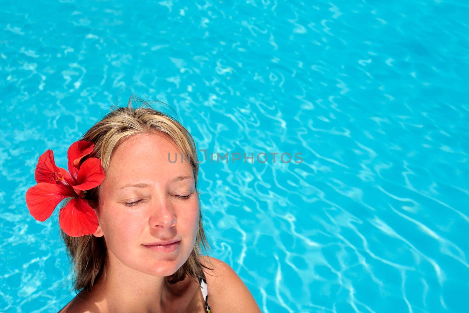 Woman sunbathing by blue swimming pool