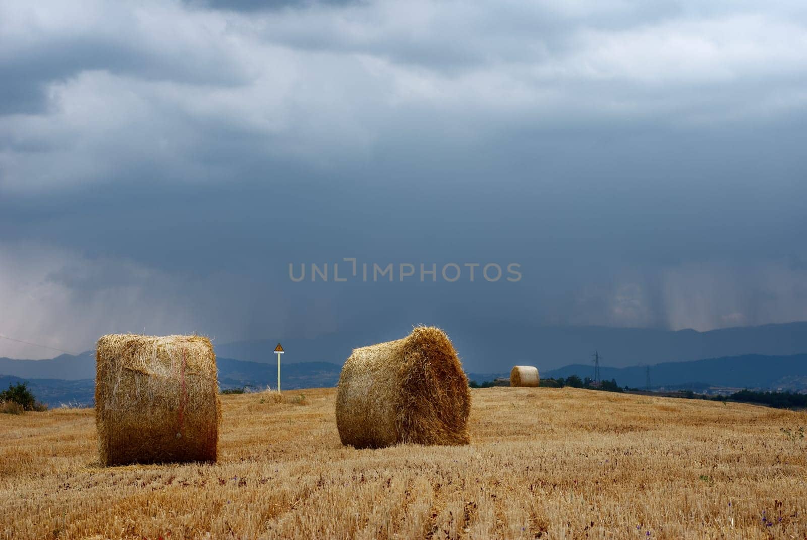 Straw bales in a field under moody sky