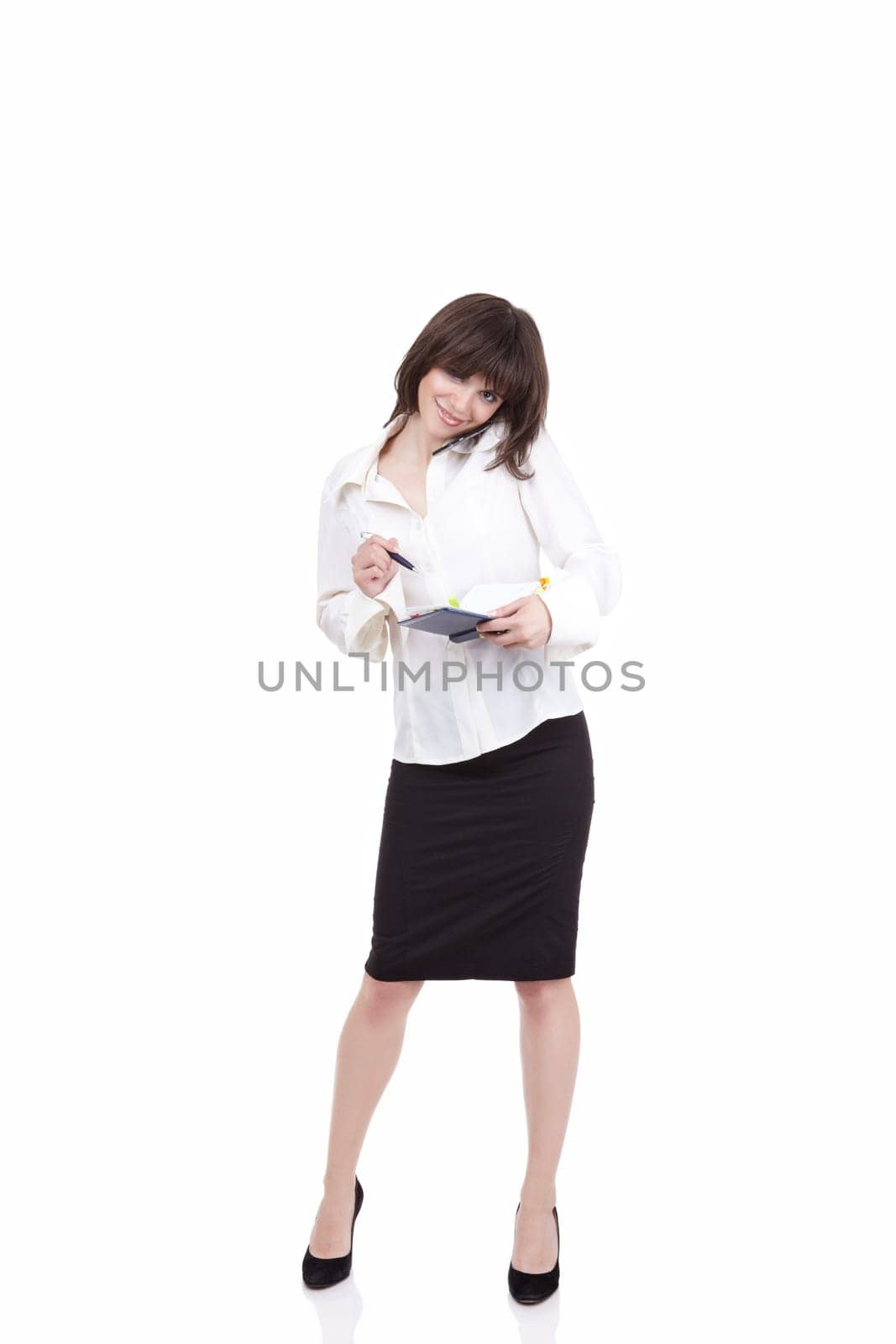 The beautiful girl speaks by phone and is going to write to a notebook