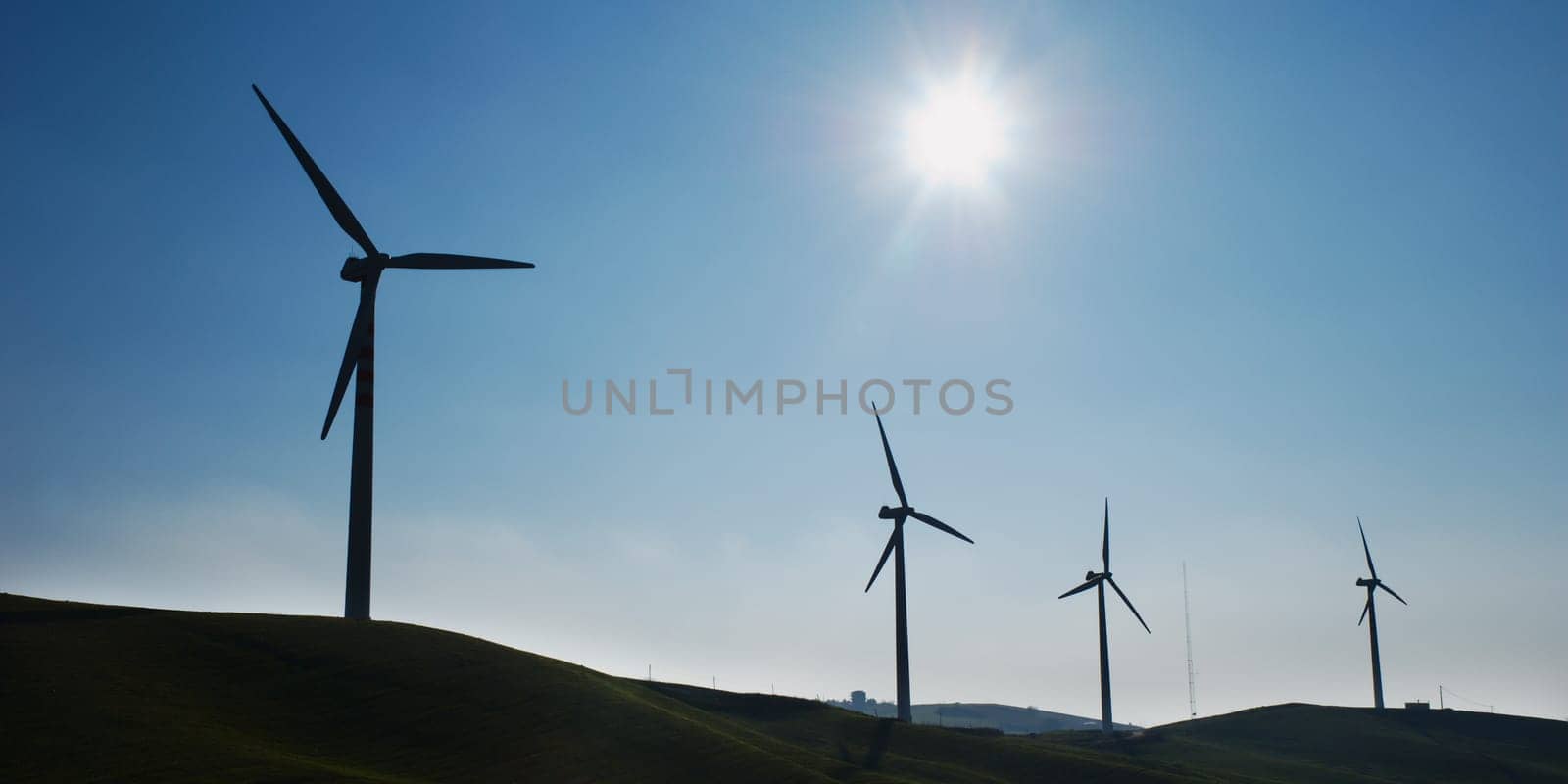 Four wind turbines silhouettes on top of hill
