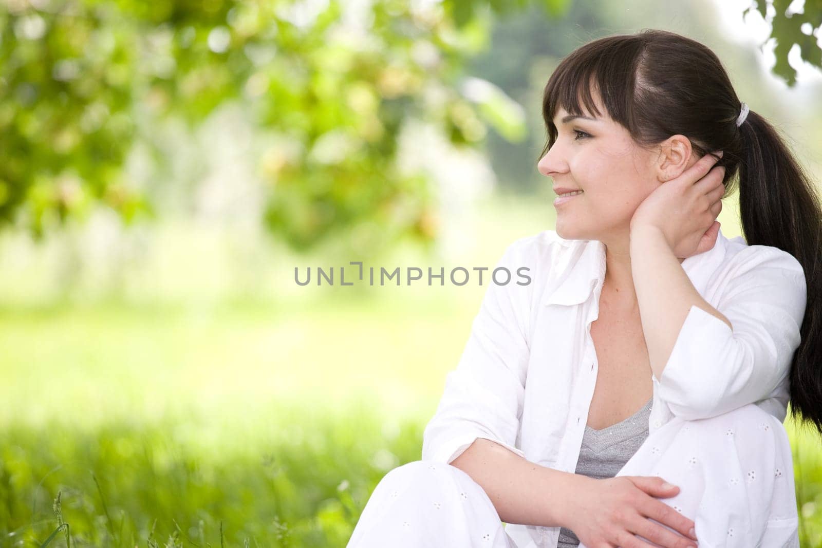 attractive brunette woman relaxing on grass