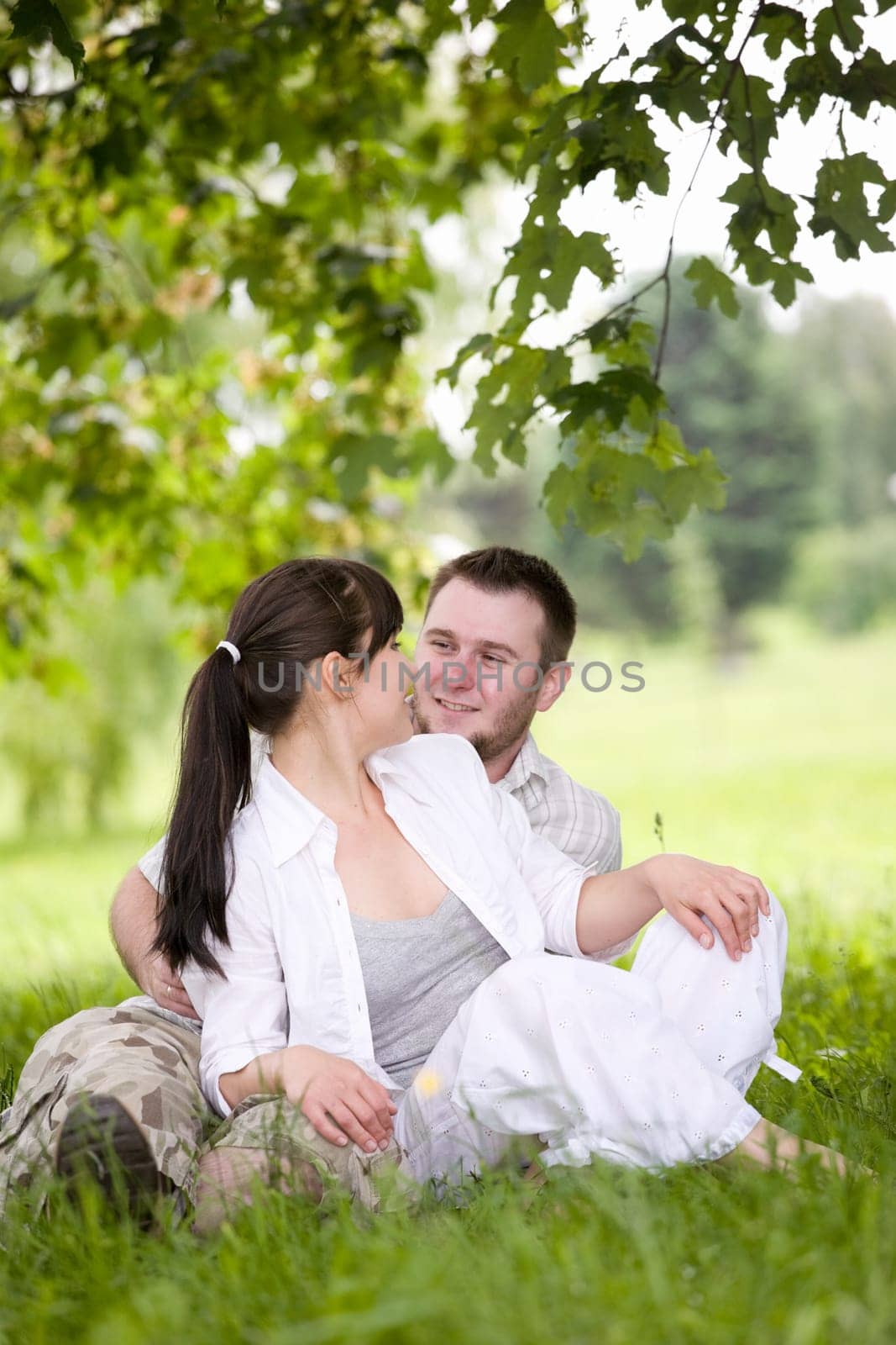 happy couple together sitting on grass