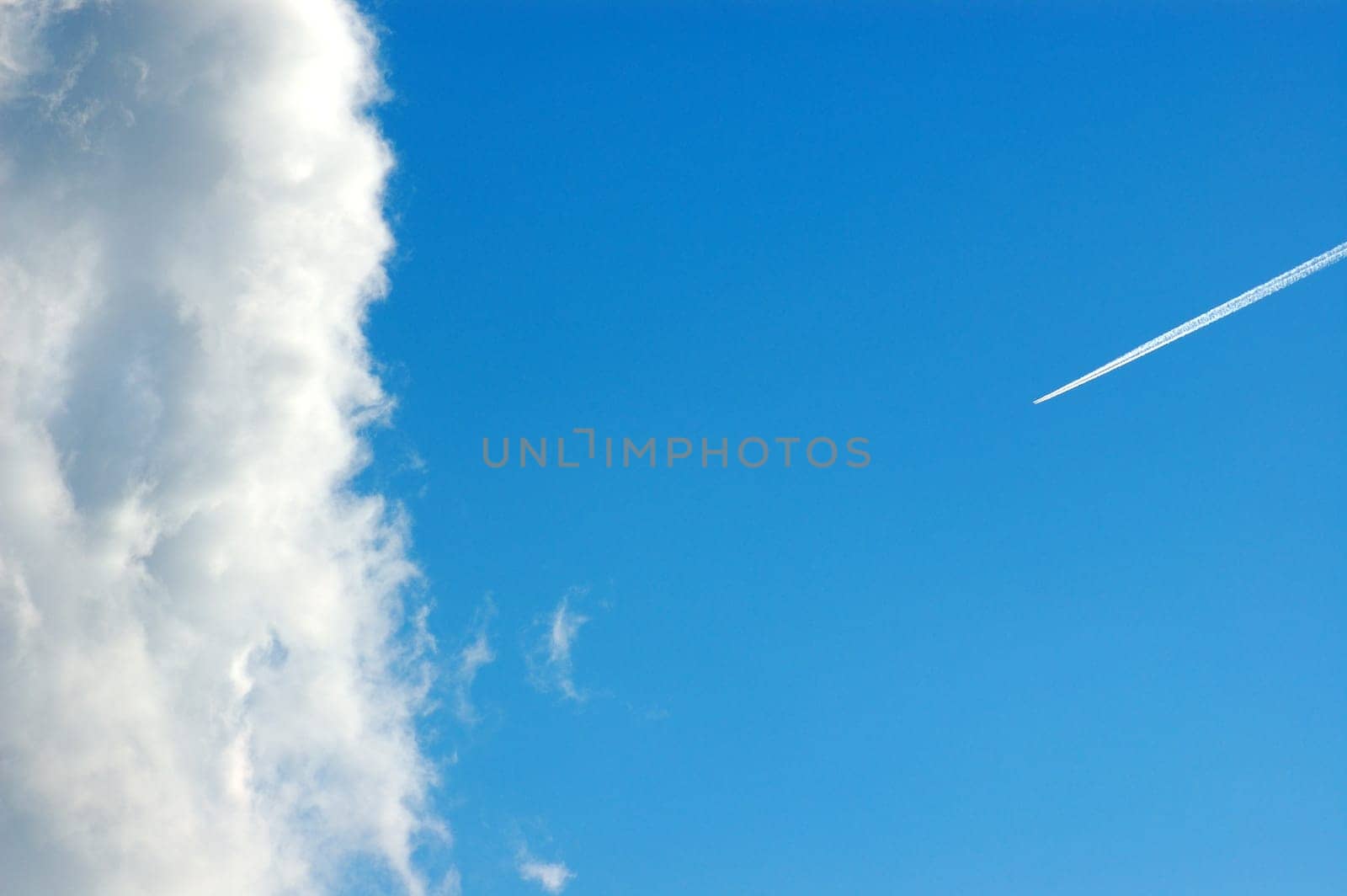 Cloud against a blue sky and airplane smoke trail.