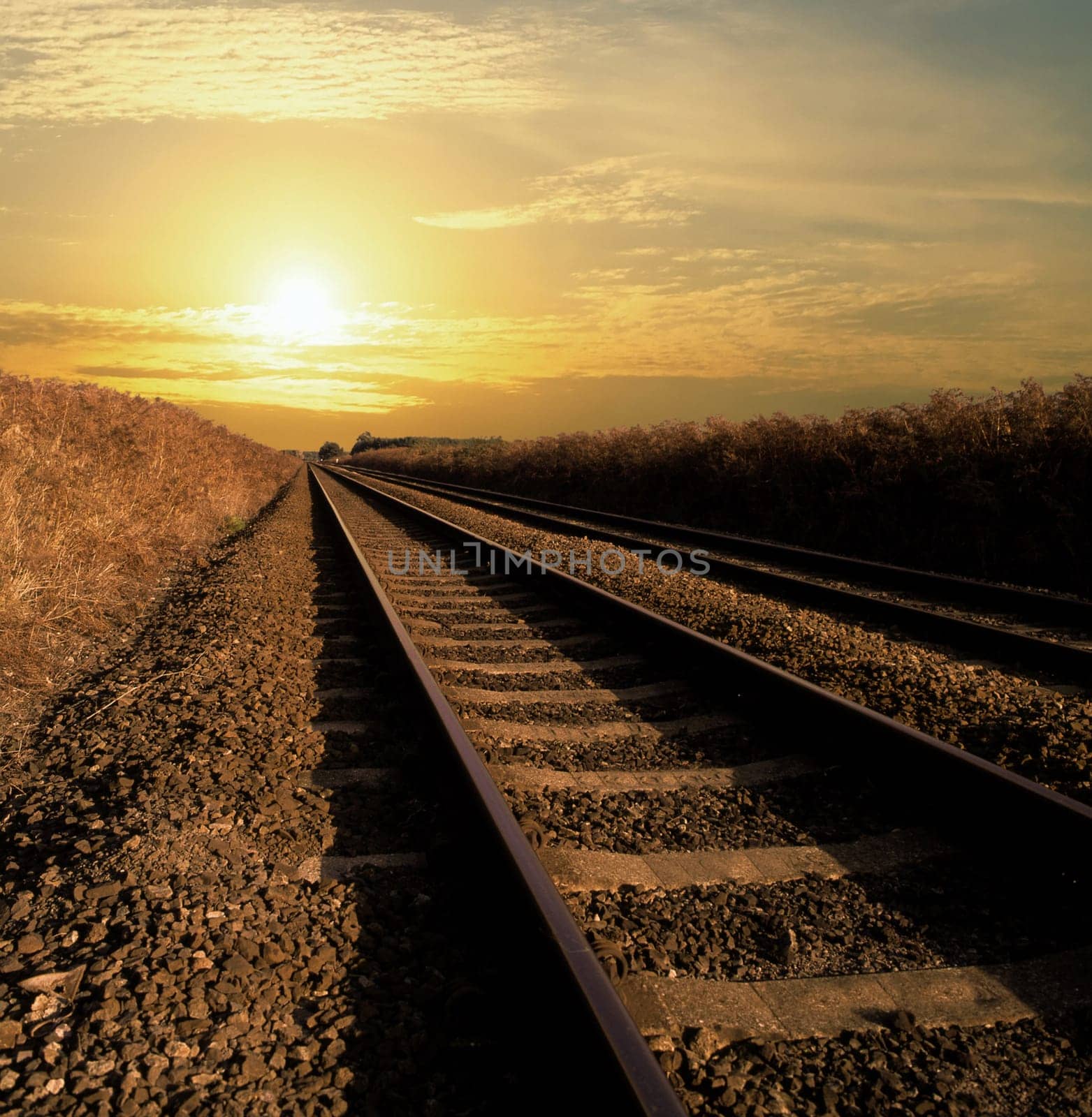 Rail track going into infinity with the sun setting