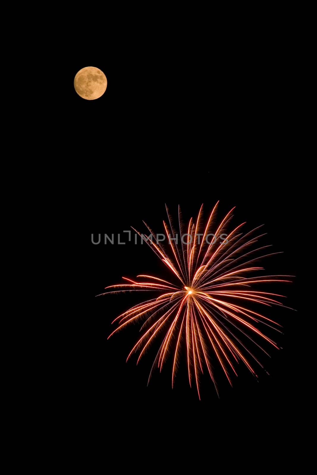 A red and yellow fireworks bursting near the moon.