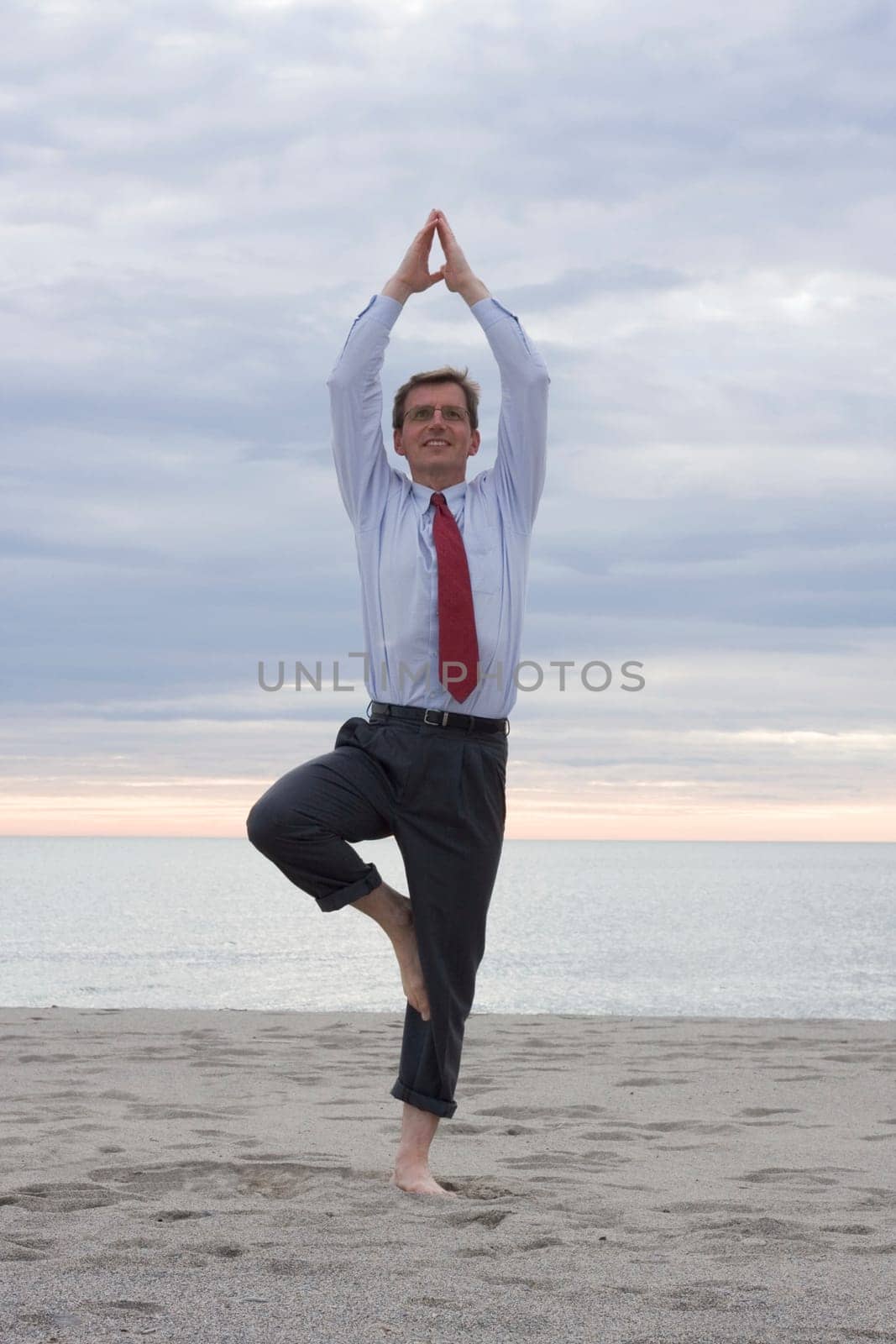 Businessman doing yoga on a beach