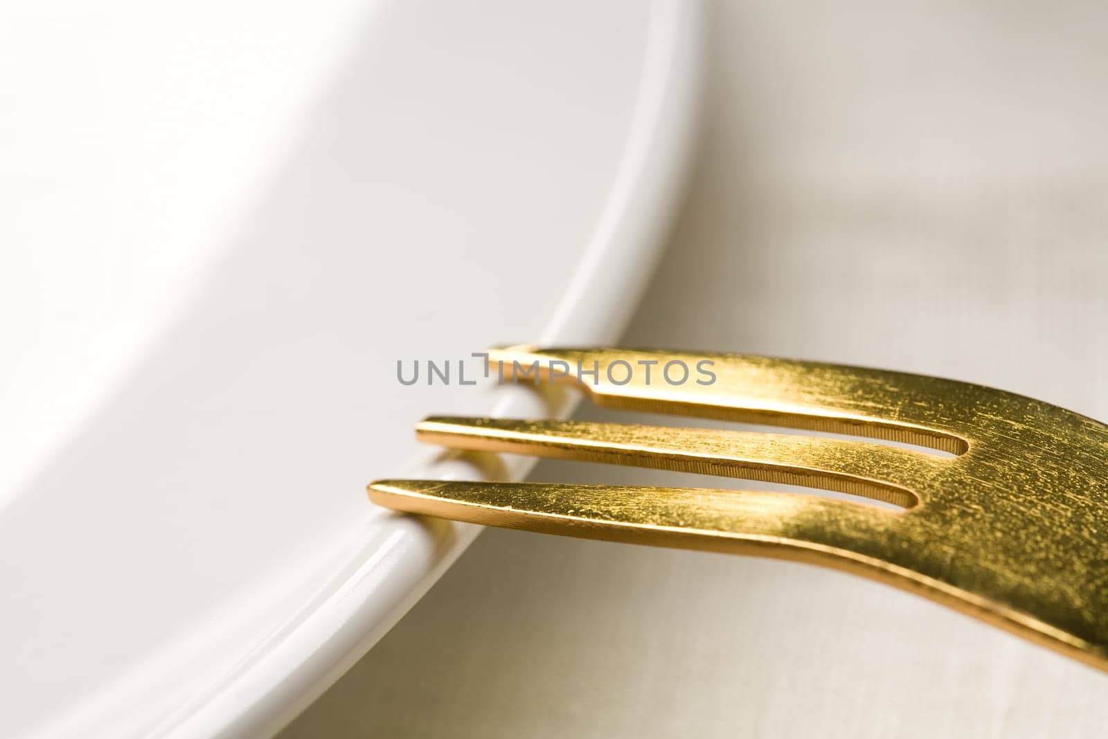 Fragment of kitchen ware - a white plate and a Gold fork on a plate