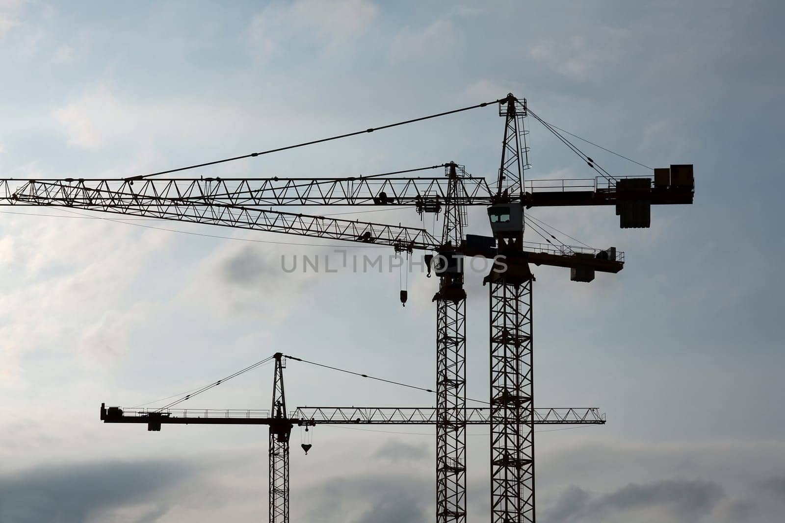 Tower crane silhouettes against cloudy sky