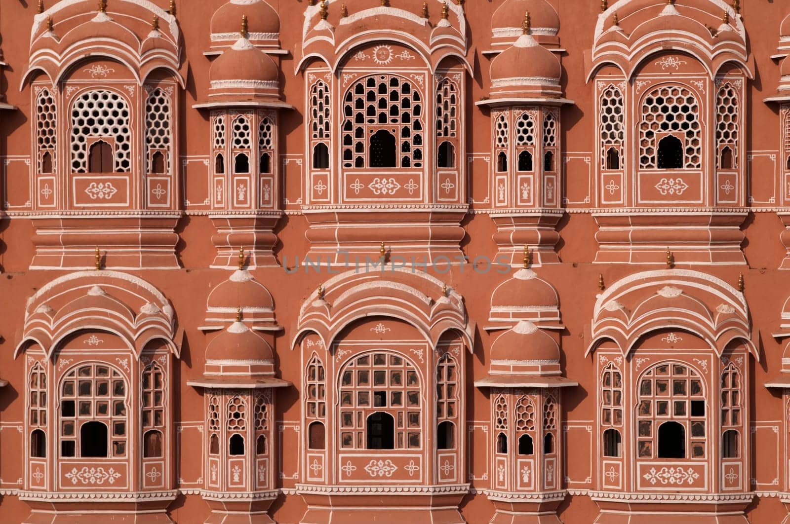 The Hawa Mahal or Palace of the Winds. Ornate pink and gold facade built to allow the ladies of the harem to view the streets below without being seen. Jaipur, Rajasthan, India