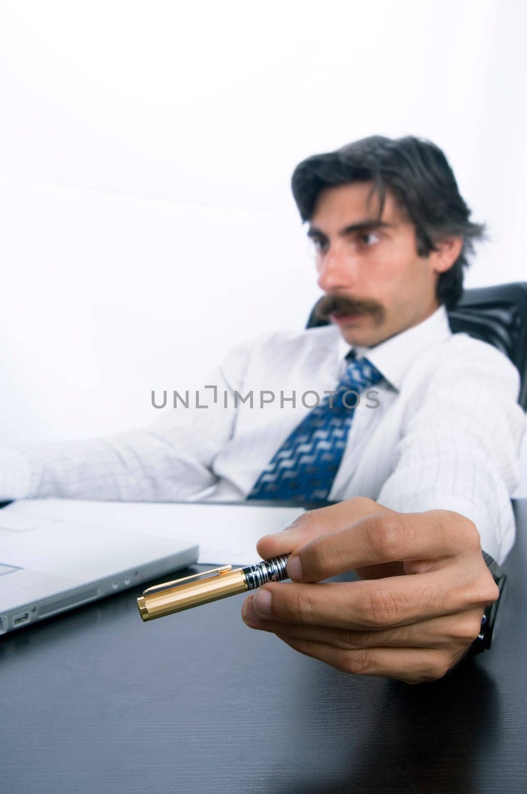 Businessman at his desk, concentrating on his job and playing with his pen