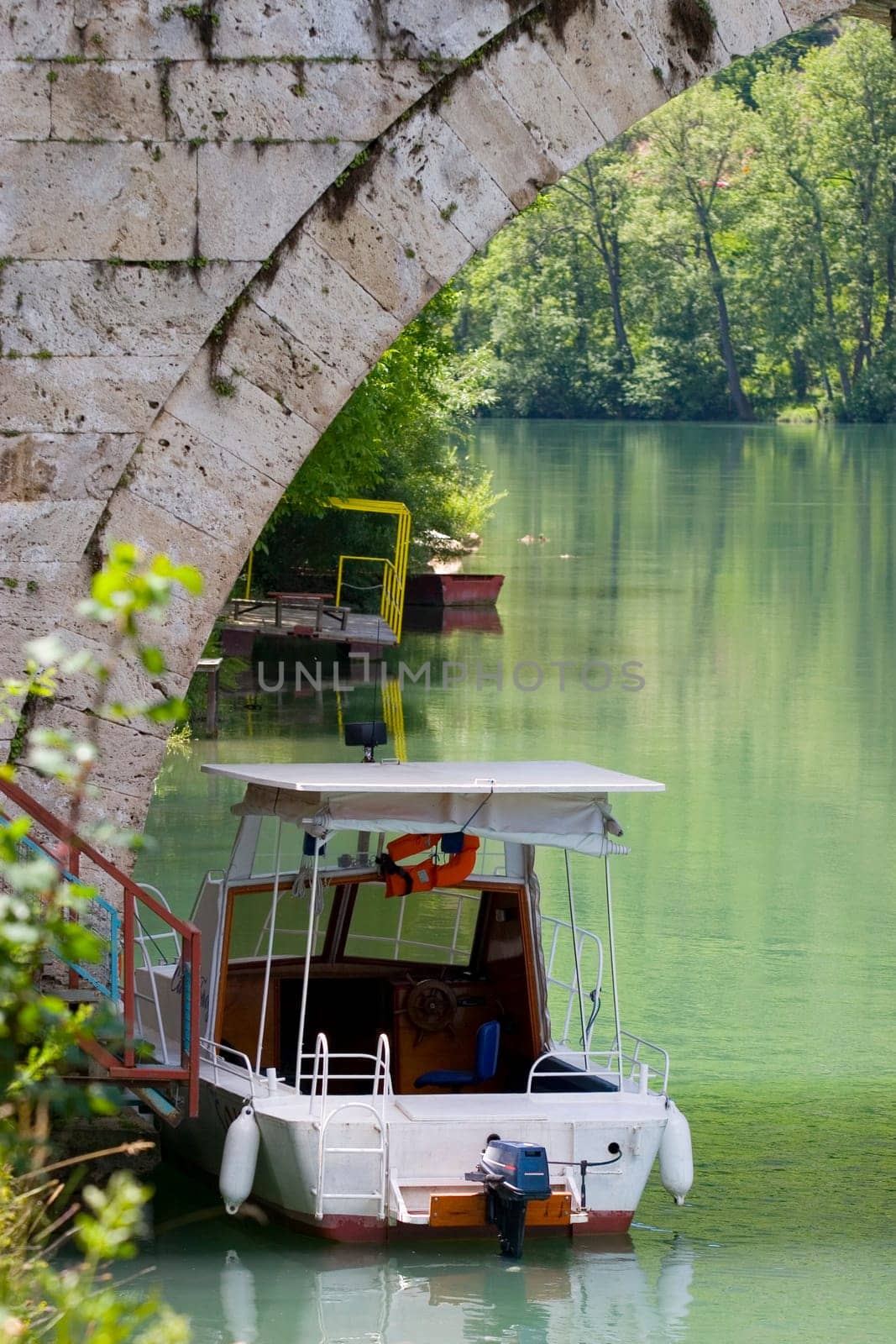 A small boat under an old stone bridge